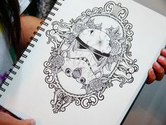 a person holding a notebook with a drawing of a storm trooper helmet and flowers on it