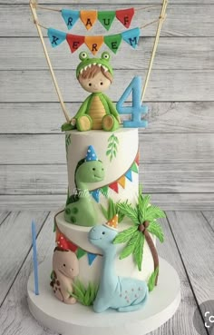 a three tiered birthday cake decorated with dinosaurs and bunting flags on a wooden table