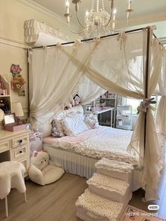 a white bed sitting in a bedroom next to a dresser and table with a chandelier on top of it