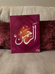 an arabic calligraphy is displayed on a couch with red pillows and a pillow in the foreground