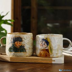 two coffee mugs sitting on top of a wooden table