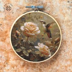 a cross stitch pattern with flowers and hummingbirds in flight, on a marble surface