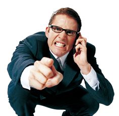 a man in a suit and glasses pointing at the camera with his hand on his ear