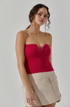 a woman wearing a red top and tan skirt