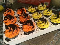 cupcakes with yellow and black frosting on a tray