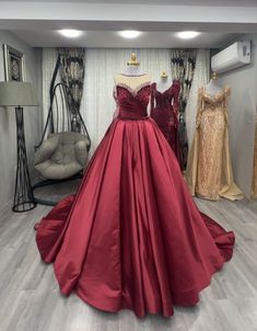 a red ball gown is on display in front of mannequins and dresses