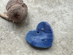 a blue heart shaped object sitting on top of a cement ground next to a dead flower