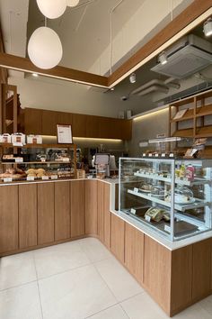 the inside of a bakery with lots of food on display behind glass shelves and lights hanging from the ceiling