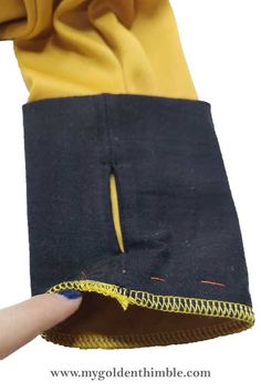 someone is stitching the zipper on a black and yellow piece of fabric with scissors