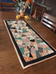 a wooden table with a quilt on it and flowers in a vase next to it