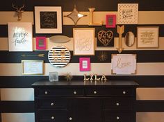 a black and white striped wall with lots of framed pictures on the wall above it