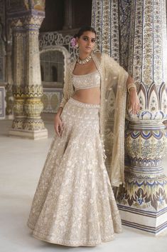 a woman in a white and gold lehenga is posing for the camera with her hand on her hip