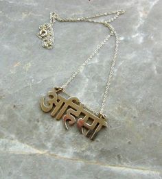 a necklace with the word india on it sitting on top of a stone slab next to a chain