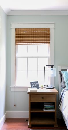 a bed room with a neatly made bed and a night stand next to the window