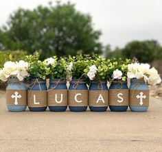 four blue vases with white flowers and the word lucas painted on them are tied to burlocks