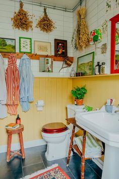 a bathroom with yellow walls and pictures on the wall