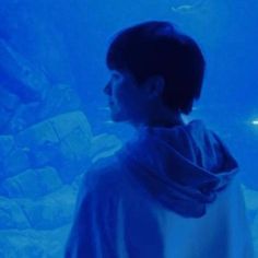 a man standing in front of an aquarium looking at the fish swimming around his neck