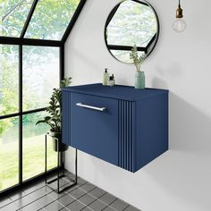 a bathroom with a blue cabinet next to a window and a round mirror on the wall