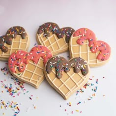 four heart shaped waffles with chocolate frosting and sprinkles on them