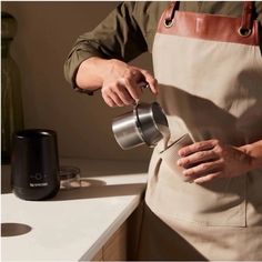 a person in an apron pours coffee into a cup