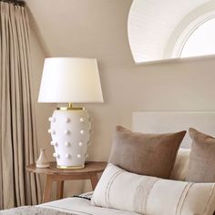 a white lamp sitting on top of a table next to a bed in a bedroom