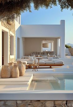 an outdoor living area with couches, tables and water feature in the foreground