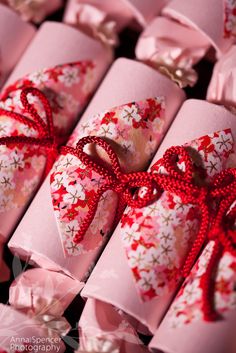 pink wrapped presents with red ribbons and bows on them, all lined up next to each other