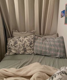 an unmade bed with pillows and blankets on it