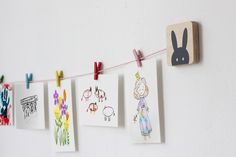 some pictures hanging on a line with clothes pins and magnets attached to the string