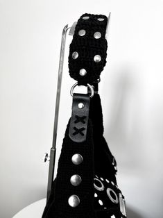 a black purse with metal rivets on the handle and straps attached to it