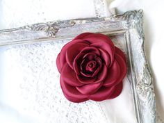 "Beautiful, delicate satin camellia flower with burgundy red /or other colour/ silk /satin/, perfect for wedding and parties. This flower brooch is the perfect addition to your outfit. It looks stunning on hats, jackets, dresses, scarfs, purses and clutches alike. Size: approx. /shown in picture/ 3\" (~8.5 cm) in diameter. If you need a flower of a different colour, or more than one flower, let me know! To see more flower brooches and hair accessories, just click the link: https://www.etsy.com/s Red Handmade Flower Brooches For Wedding, Pink Flower Hair Clip, Gold Leaf Crown, Brooch Fabric, Red Camellia, Rose Gold Flower, Camellia Flower, Maroon Red, Wine Color