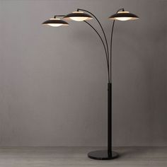 a lamp that is on top of a wooden floor in front of a gray wall