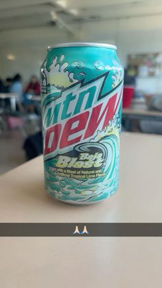 a can of mountain dew sitting on top of a table in an office building with people working behind it