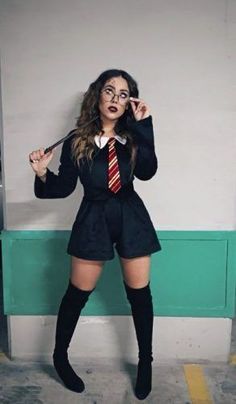 a woman dressed as harry potter holding a wand and posing in front of a wall