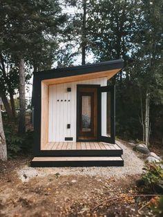 a tiny house built in the woods with wood floors and black trim on the door