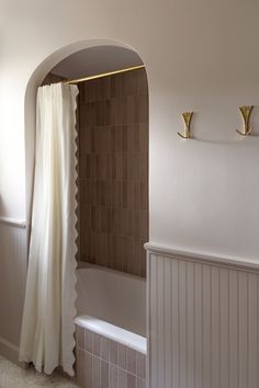 a bath room with a toilet and a bath tub next to a wall mounted shower head