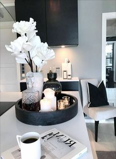 a tray with flowers and candles on top of a table in a living room area