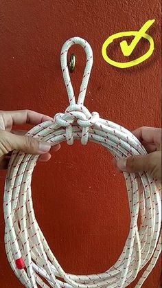 two hands are holding a white rope against a red wall