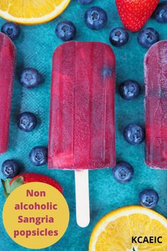 three popsicles with blueberries, oranges and strawberries on them