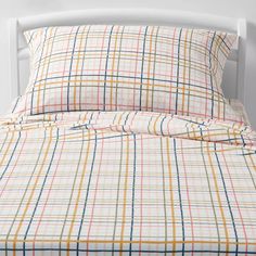 a bed with plaid sheets and pillows on it