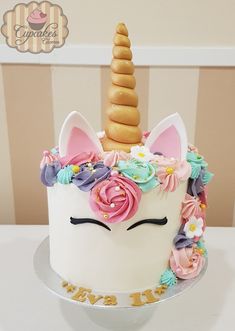 a white cake decorated with flowers and a unicorn's horn