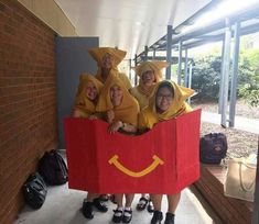 four people dressed in costumes are posing for a photo with a bag that looks like mcdonald's