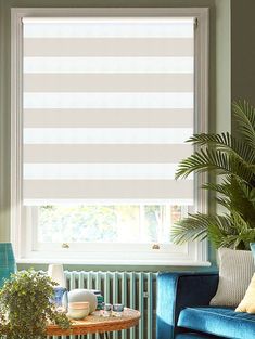 a living room filled with furniture and a window covered in roman shades on the windowsill