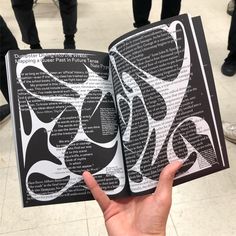 a person holding an open book with black and white designs on it's pages