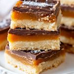 several pieces of cake sitting on top of a white plate covered in chocolate and caramel