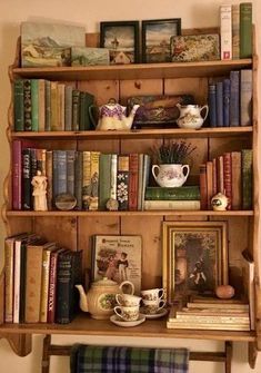 an old book shelf with books and tea cups on it