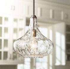 a glass light fixture hanging from a ceiling in a room with white walls and windows