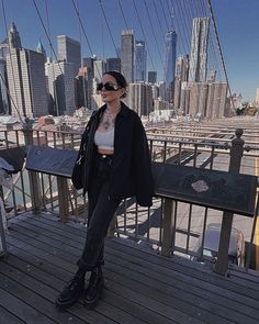 a woman standing on top of a wooden bridge