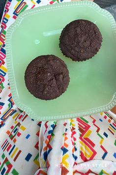 two chocolate cookies sitting on top of a green plate