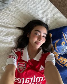 a young woman laying on top of a bed next to a blue and white pillow